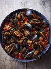 Bowl of mediterranean mussels and vegetables on table — Stock Photo
