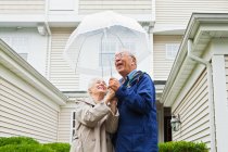 Старшая пара держит зонтик снаружи — стоковое фото