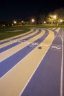 Running track with numbers and lanterns at night — Stock Photo