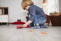 Молодий хлопчик грає з іграшковою пиломатерією і пензлем — стокове фото