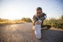 Jovem mulher exercitando e alongando a perna em ambiente rural — Fotografia de Stock