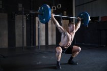 Homem se exercitando no ginásio, usando barra, posição de agachamento frontal — Fotografia de Stock