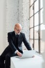 Бизнесмен с очками на подоконнике с помощью ноутбука — стоковое фото