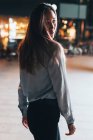 Portrait of woman outdoors at night looking over shoulder — Stock Photo