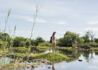 Distant side view of Young female tourist looking out over calm waters near Victoria Falls, Zimbabwe, Africa — Stock Photo