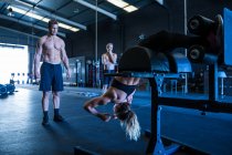 Three people exercising in gymnasium, using equipment — Stock Photo