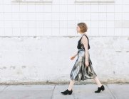 Vista laterale della donna in gonna metallica che cammina sulla strada — Foto stock