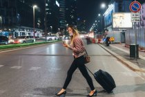 Жінка виходить на вулицю з колісною валізою — стокове фото