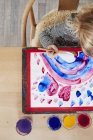 Young girl at table painting picture — Stock Photo
