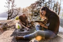 Man and woman relaxing, cooking food and playing guitar on The Malamute, Squamish, Canada — Stock Photo