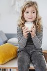 Giovane ragazza in soggiorno con in mano un bicchiere di latte — Foto stock
