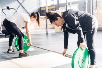 Mujeres preparando equipos de pesas en el gimnasio - foto de stock