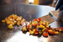 Abgeschnittenes Bild von Koch, der Gemüse auf flachem Grill zubereitet — Stockfoto