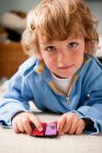 Young boy playing at home with two toy cars — Stock Photo