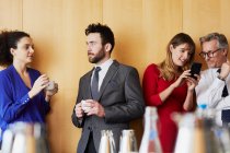 Бізнес-леді та чоловіки спілкуються перед офісною зустріччю — стокове фото