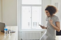 Geschäftsfrau im Büro textet auf Smartphone — Stockfoto