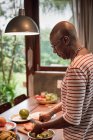 Reifer Mann am Küchentisch bereitet Obst in Schüssel zu — Stockfoto