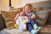 Menina e irmã bebê no sofá, retrato — Fotografia de Stock