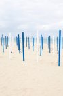 Polos de paraguas de playa blancos y azules en la playa de arena - foto de stock
