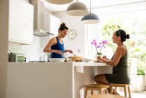 Two friends enjoying salad lunch on kitchen — Stock Photo