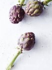 Still life of fresh healthy artichokes on white, top view — Stock Photo