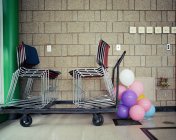 Cadeiras e balões colocados por parede dentro de casa — Fotografia de Stock