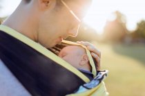 Father carrying baby boy in baby carrier — Stock Photo