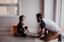 Дівчина допомагає батькові встановлювати плитку для підлоги — стокове фото