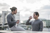 Молодые близнецы-мужчины берут на тренировку перерыв и питьевую воду — стоковое фото