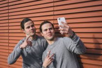 Молодые близнецы-мужчины делают перерыв на тренировку и селфи — стоковое фото