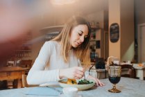 Mujer comiendo comida vegana en el restaurante - foto de stock
