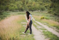 Вид на далёкую сторону молодой женщины-туристки на грунтовой дорожке в Национальном парке Крюгер, вид через плечо, Южная Африка — стоковое фото