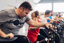 People in gym using exercise bikes — Stock Photo