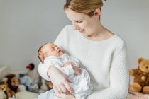 Мати тримає новонароджену дівчинку, посміхаючись — стокове фото