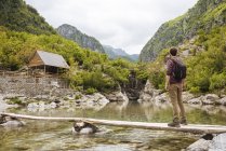 Man on wooden bridge looking at cabin, Accursed mountains, Theth, Shkoder, Albania, Europe — Stock Photo
