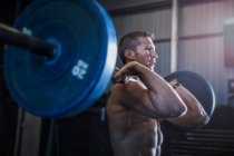 Man exercising in gym, using barbell, front squat position — Stock Photo