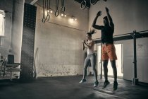 Мужчина и женщина в спортзале прыгают в воздухе — стоковое фото