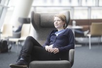 Frau macht Pause und sitzt im Sessel im Büro — Stockfoto