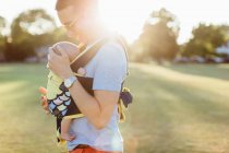 Father carrying baby boy in baby carrier — Stock Photo