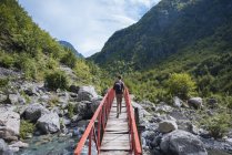 Rückansicht eines Mannes, der eine Brücke in den verfluchten Bergen überquert, theth, shkoder, albanien, europa — Stockfoto