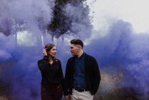 Junges Paar hält Hand an blauer Rauchwolke — Stockfoto