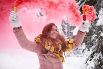 Giovane donna con brillamento di fumo nella neve — Foto stock