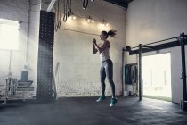 Woman in gym jumping in mid air — Stock Photo