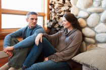 Retrato de pareja adulta sentada en cabaña de madera - foto de stock