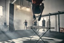 Человек в воздухе прыгает с барьерами в спортзале — стоковое фото