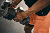 Cropped view of man using dumbbells — Stock Photo