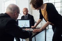 Colleagues looking at graphical data on laptop — Stock Photo