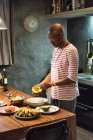 Uomo maturo al tavolo da cucina preparare avocado — Foto stock