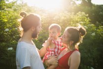 Paar mit Baby im sonnenbeschienenen Garten — Stockfoto