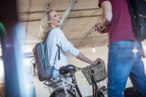 Mujer joven con colega de bienvenida en bicicleta en la oficina - foto de stock